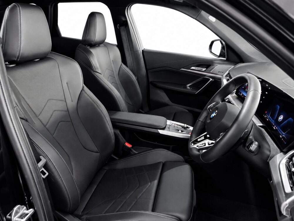 Luxurious black leather car interior with stitched seats, digital dashboard, and a BMW steering wheel.