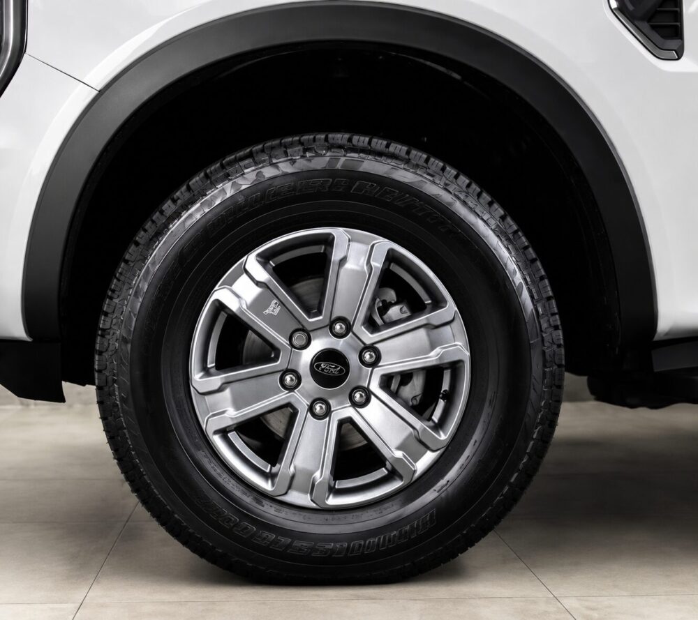 Close-up of a car wheel with a silver alloy rim and Bridgestone tire on a white vehicle