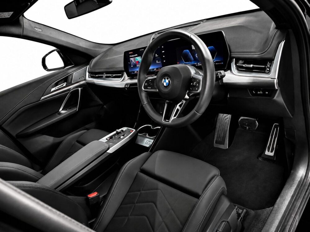 Luxurious car interior featuring a digital dashboard, steering wheel with BMW logo, and sleek center console with black leather seats.