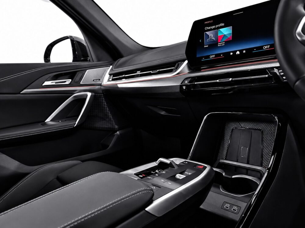 Luxury car interior with a large touchscreen infotainment display, sleek metallic trims, and leather seats with white stitching