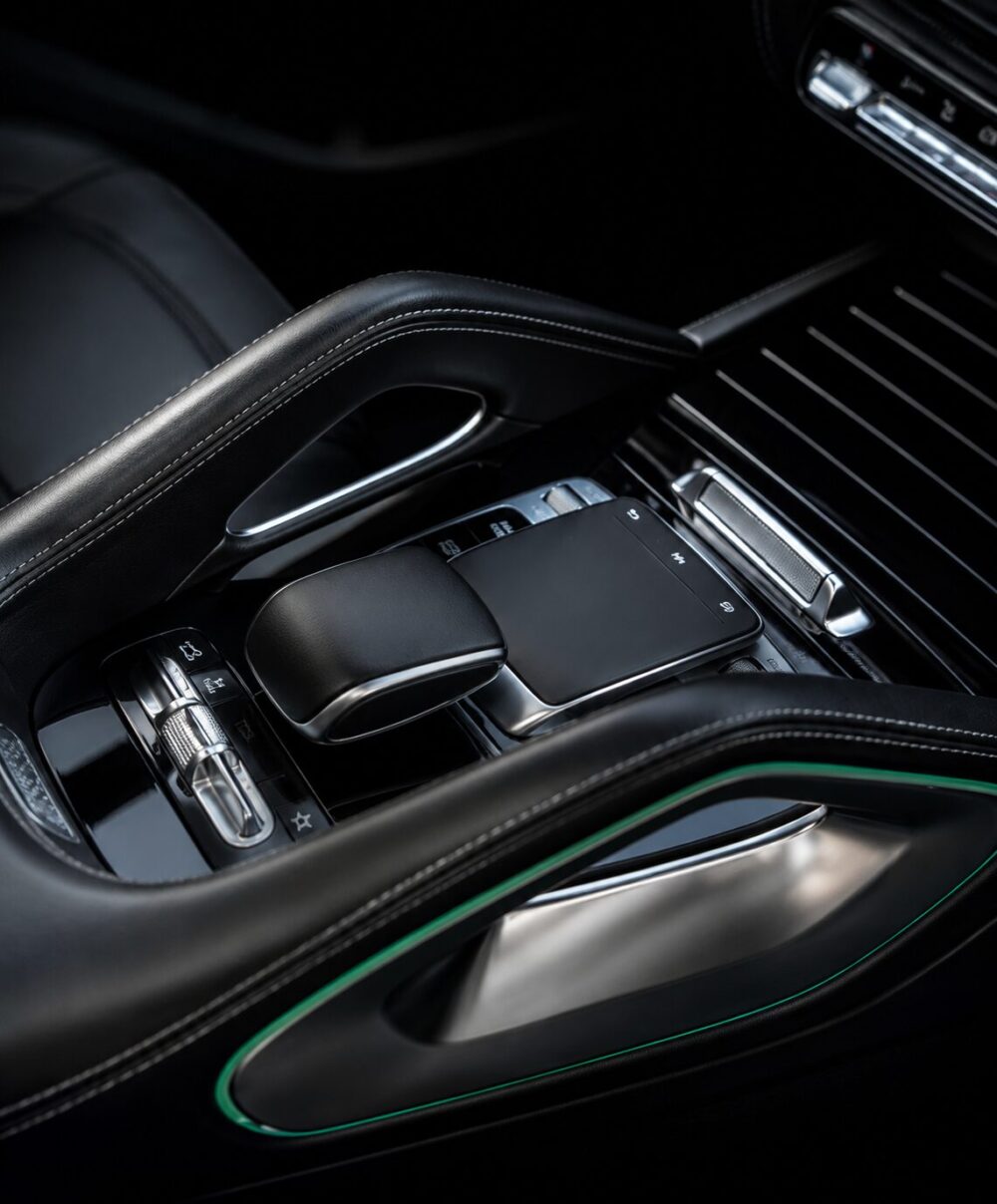 Close-up of a luxury car center console with black leather armrest, touchpad, and chrome controls.