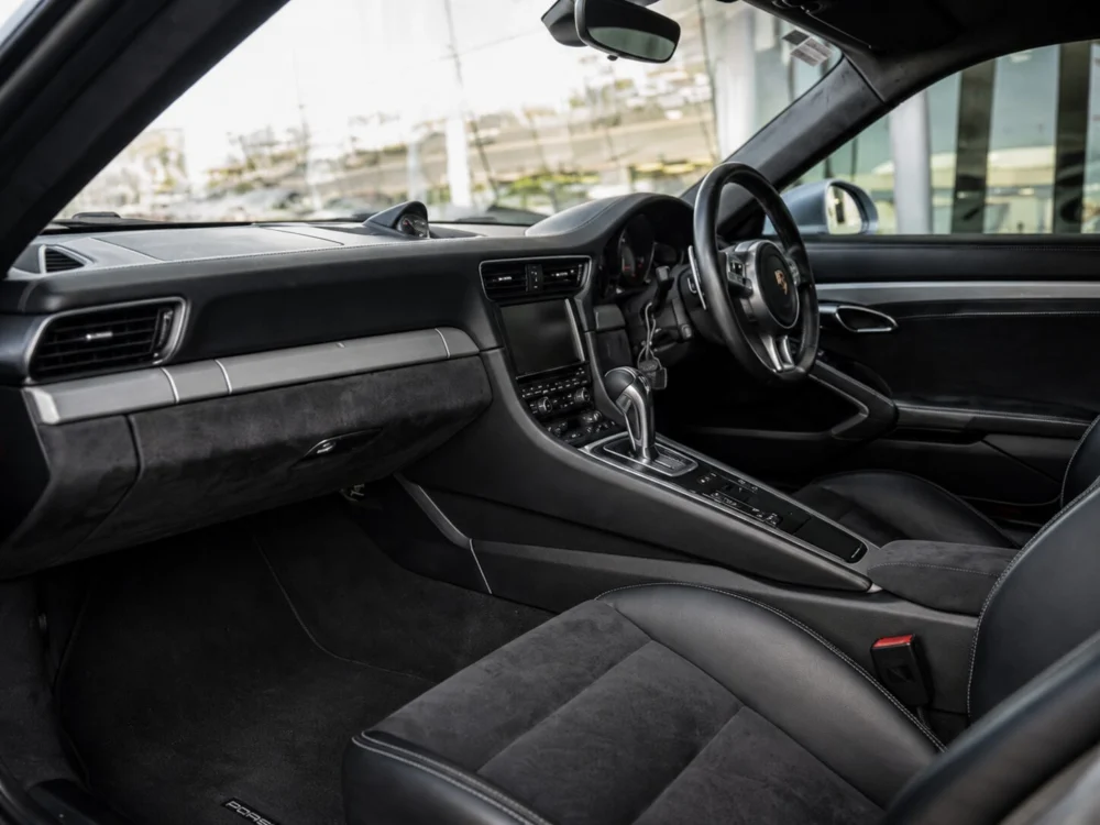 Luxurious black Porsche interior with leather seats, central touchscreen, and gear shifter in view.