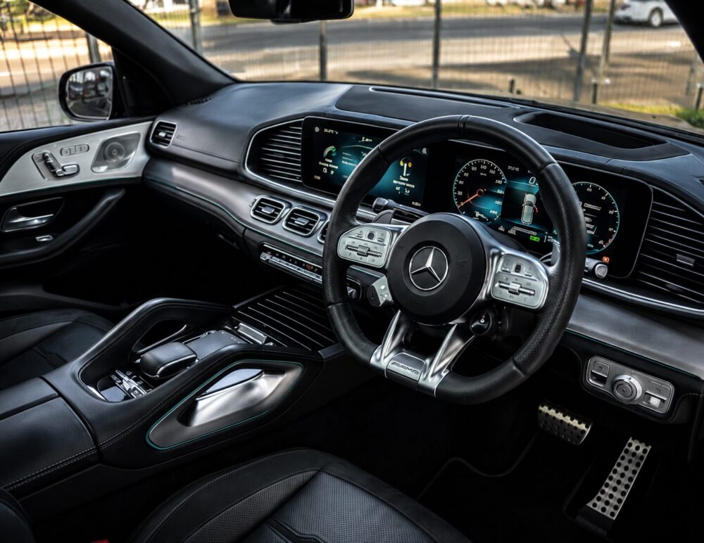 Luxurious car interior featuring a digital dashboard, steering wheel with Mercedes logo, and black leather seats.