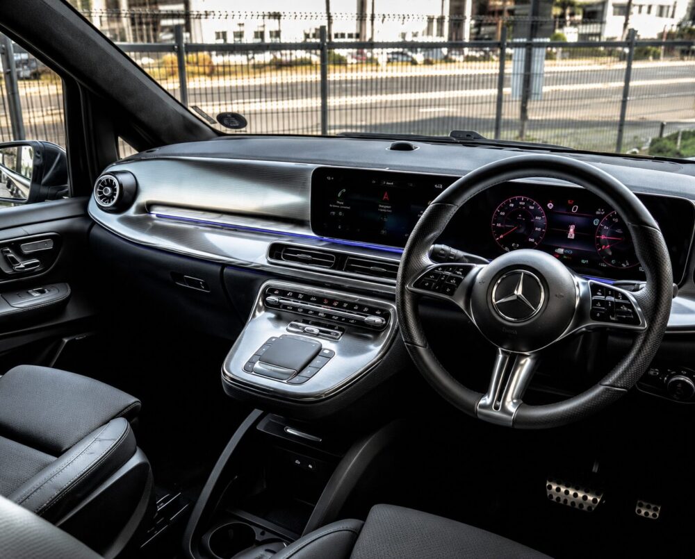 Mercedes-Benz interior with carbon-fiber trim, digital instrument cluster, and center touchscreen panel visible from the driver’s seat