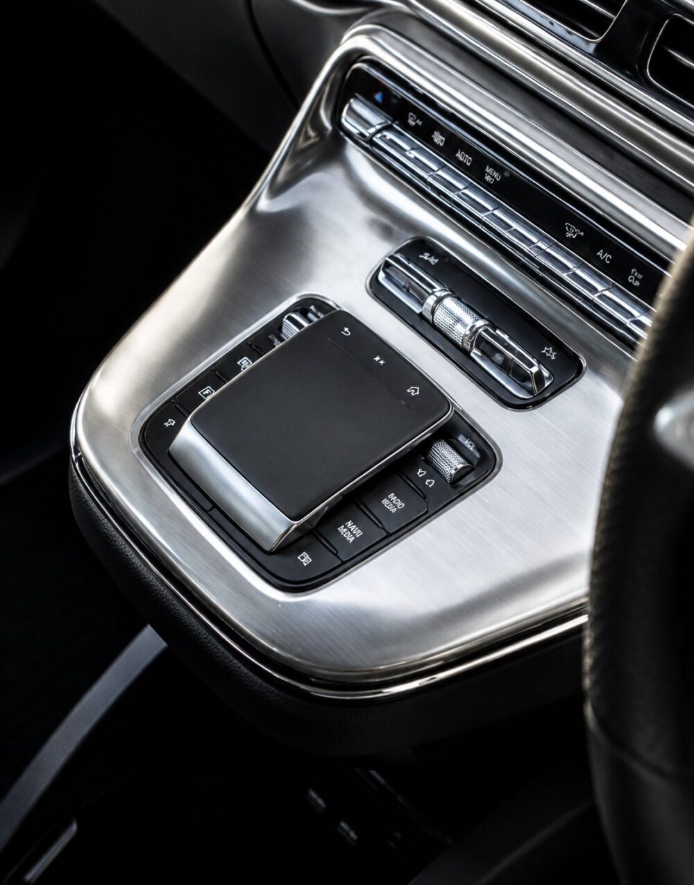 Close-up of a luxury car's center console with a large touchpad and chrome accents